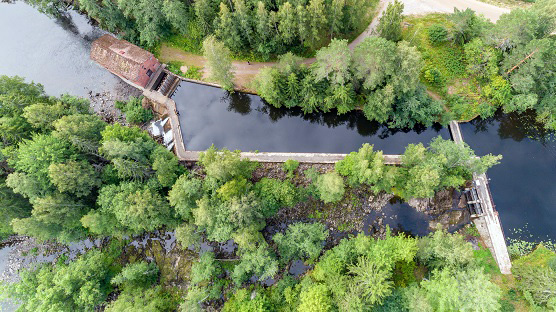 Ilmakuvassa Hiitolanjoen Kangaskosken voimala, yläkanava ja pato, kuvassa alhaalla näkyy luonnonuoma. Kuva: Arto Apila